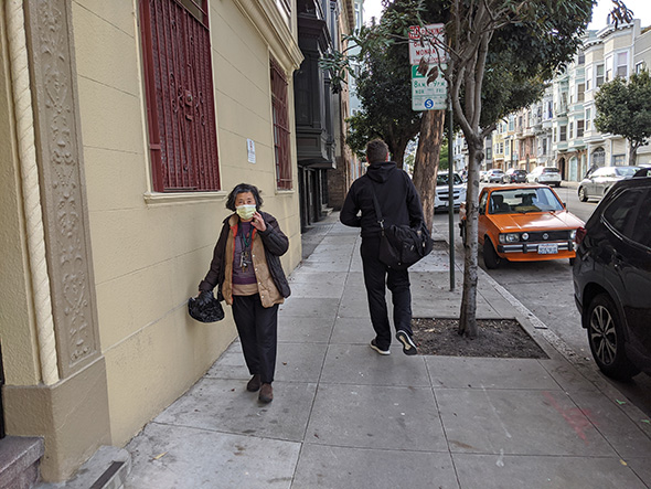 a local woman walks down the street wearing a mask